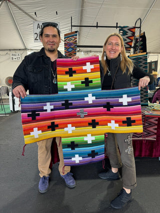 Venancio Aragon and Claire of Picayune holding up the weaving that permanently hangs in the Picayune store